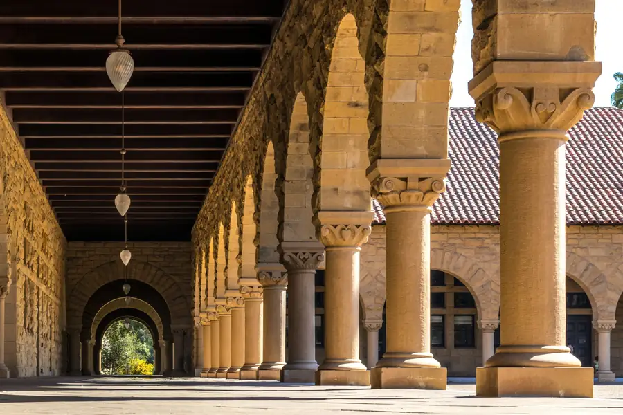 A sunlit stone arcade along a university quad
